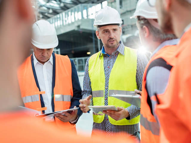 Engineers in hardhats talking to each other