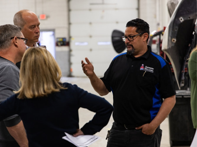 Sherwin-Williams employee talking to customers in a body shop.