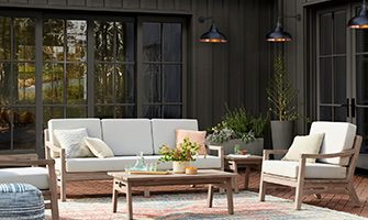 Set against a backdrop of Urbane Bronze SW 7048 (245-C7), light wood furnishings and cozy textiles create an inviting al fresco escape. Photo courtesy of Rejuvenation.