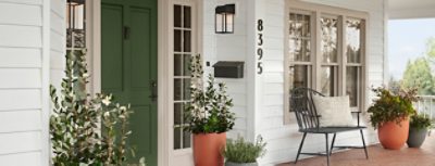 Front of a house with a porch, white siding and green front door.