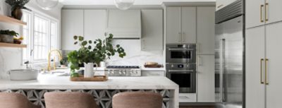 A kitchen with white marble counter tops and backsplash with light green cabinets.