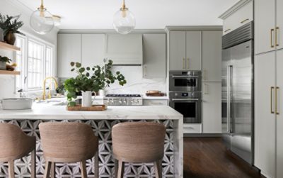 A kitchen with white marble counter tops and backsplash with light green cabinets.