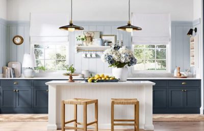 Pottery Barn kitchen walls painted in Upward SW 6239,  two windows, dark cabinets, an island with two wooden stools, and two hanging light fixtures above it.