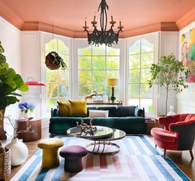 living room with a peach colored ceiling, large windows, colorful furniture.