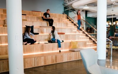 stadium type wooden seating with lighting, people interacting.