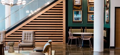 Room with chairs, green wall with picture frames, wooden panels, and wooden floors.