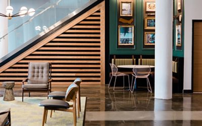 Room with chairs, green wall with picture frames, wooden panels, and wooden floors.