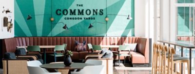 Image of the Commons Congdon Yards room with teal wall, brown leather seating near window.