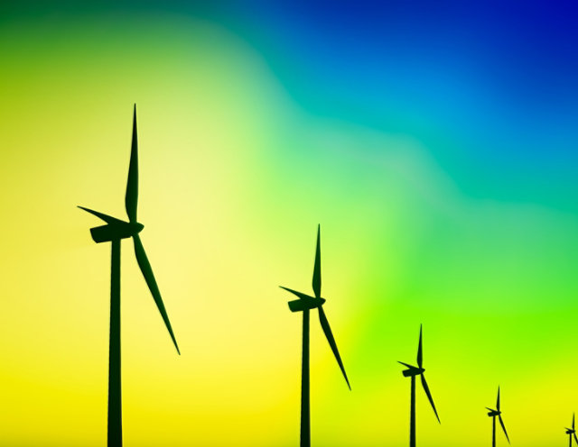Windmills in a row on the horizon with a green and blue aurora in the sky