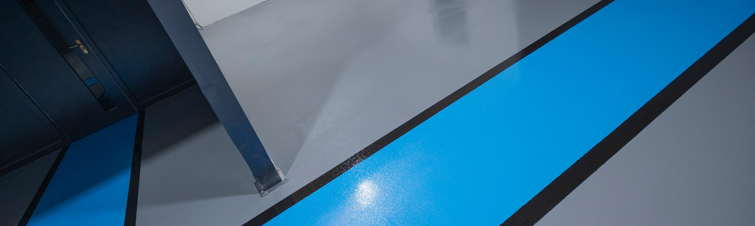 The finished result - a blue walk way demarcated with black lines against the grey Resuflor floor