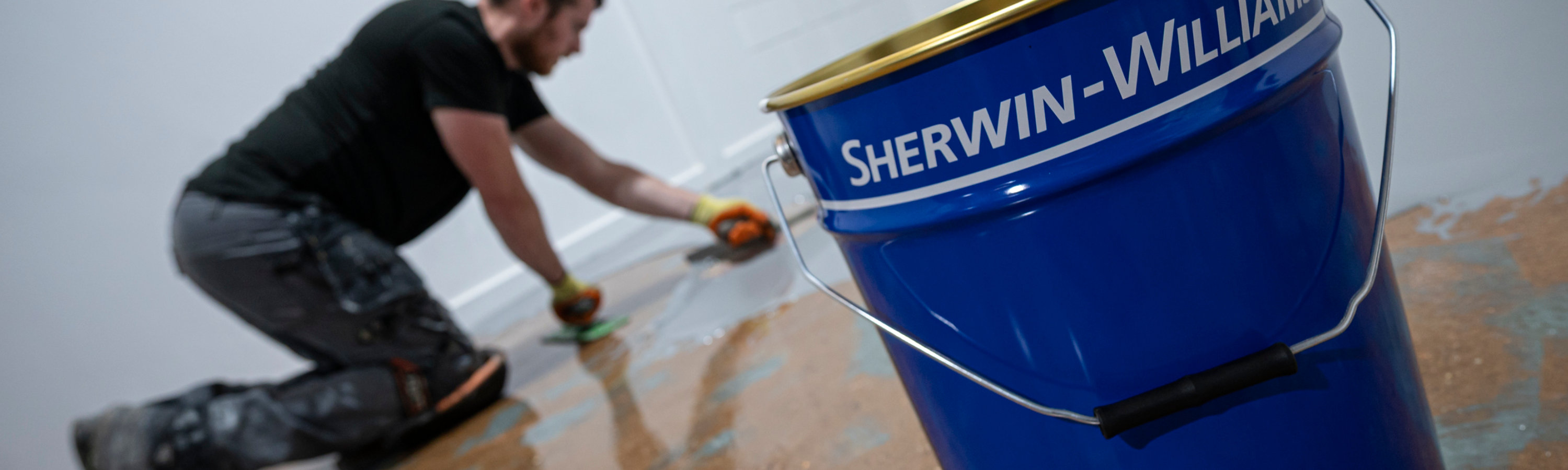 An image of an applicator smoothing out Resuflor with a spatula, with a Sherwin-Williams pail in the foreground