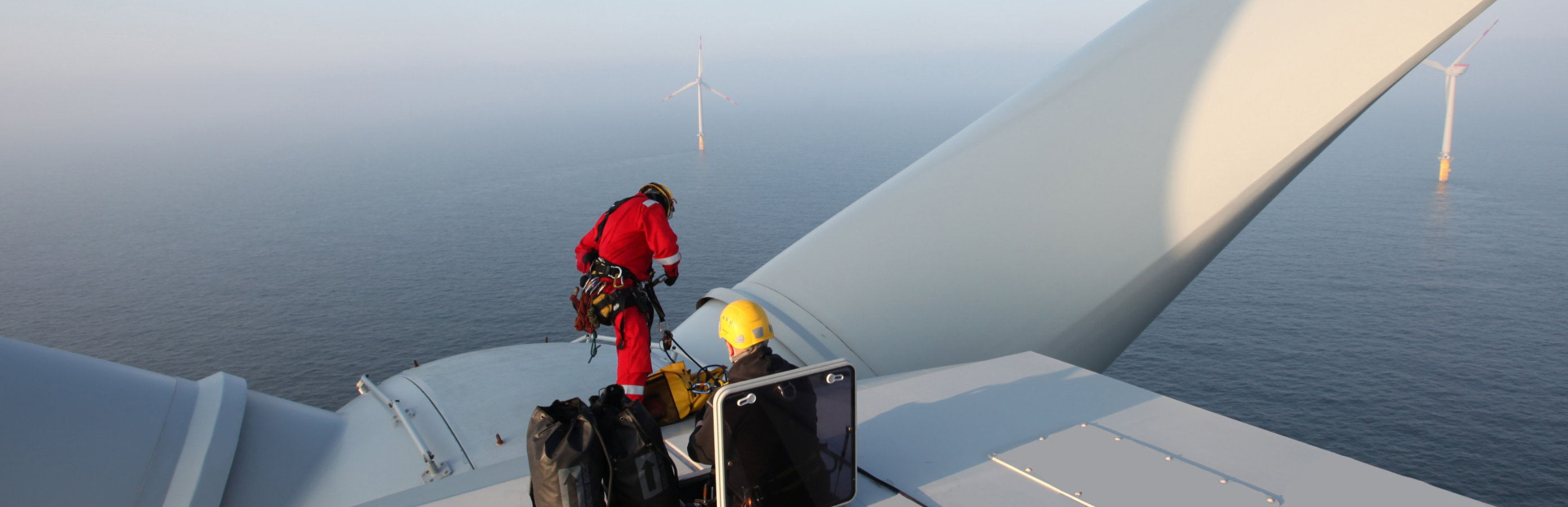 two workers on top of an offshore wind turbine