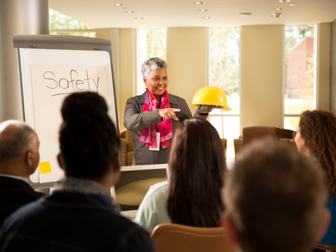 Woman standing in front of audience with white board and hard hat