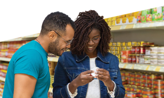 man and woman in grocery store aisle looking at canned food