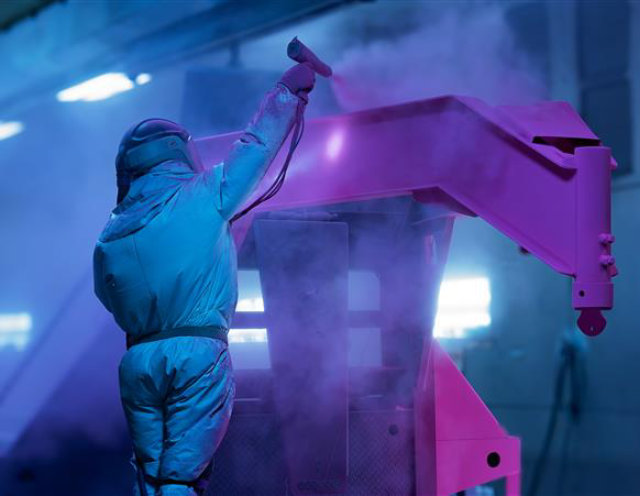 Person spraying a piece of equipment with pink powder