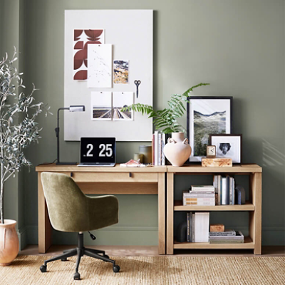 Pottery Barn office painted walls in Dried Thyme SW 6186, a large board hung above a wooden desk with a lamp, laptop, books, and decor, green desk chair, and plant.