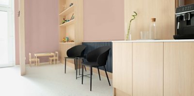 A waiting area with rose-toned walls painted with Redend Point SW 9081 (195-C4). Some black chairs next light wood cabinets and shelves.