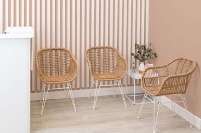 A salon waiting area with wicker chairs, white counter and circular mirror.