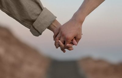 two people holding hands outside.