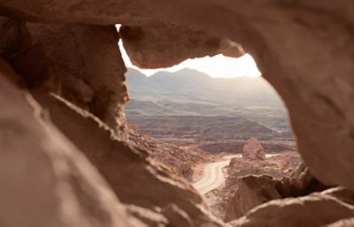 image looking through rocks onto a road surrounding hills.