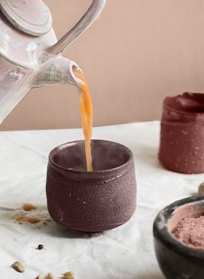 warm blush hued pottery being poured a warm drink.