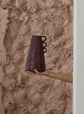 a person holding a container in front of a blush tan wall.