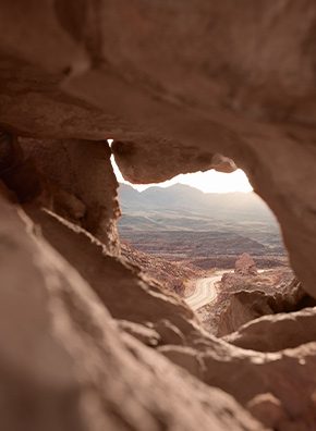 A view of a road through the opening of sandstone.