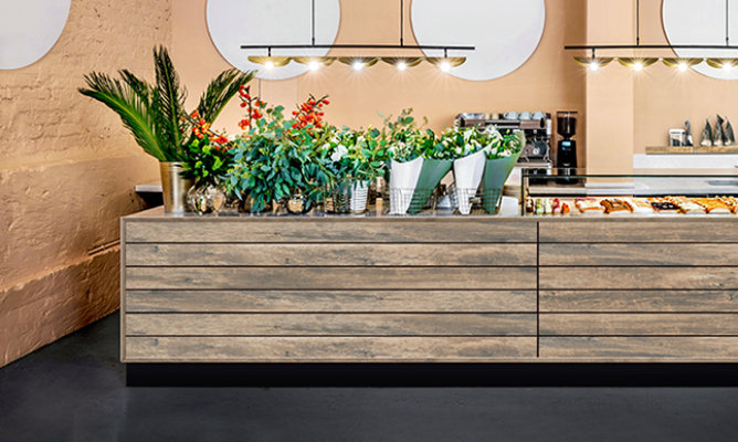 Retouched application image of cafe display featuring Sherwin-Williams Emulate Wood Barnboard pattern panels in the Rustic colorway 