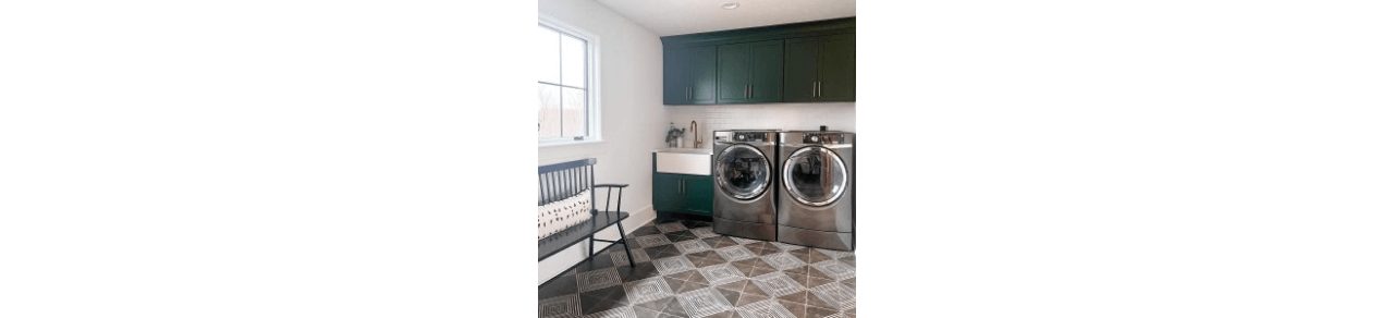 A bright, large laundry room with white painted walls and cabinets painted a forest green. 