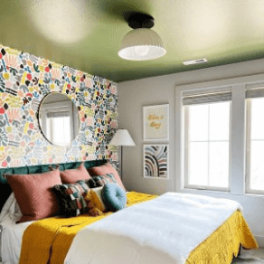 A retro style bedroom with a yellow-green painted ceiling and walls with wallpaper and white paint.
