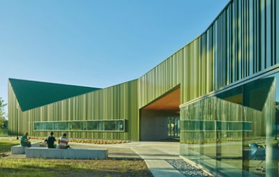 Large green building with sidewalks and some benches.