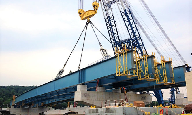 crane installing piece of bridge onto structure