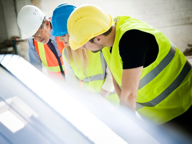 workers in hard hats looking over a document