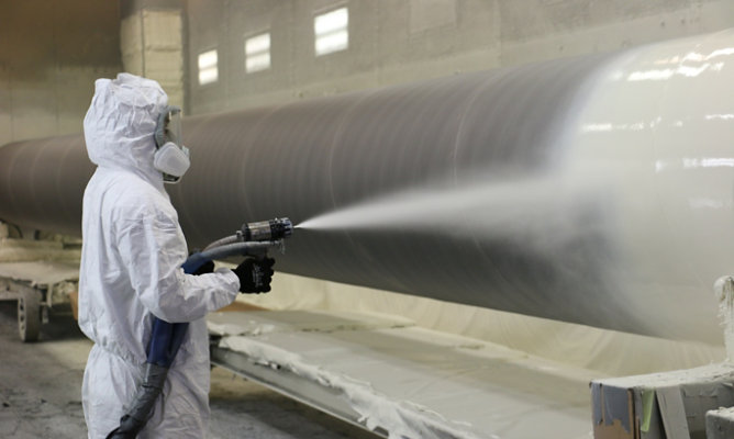 Applicators spraying quick-setting Poly-Cote 110 direct to metal on the pipe exteriors