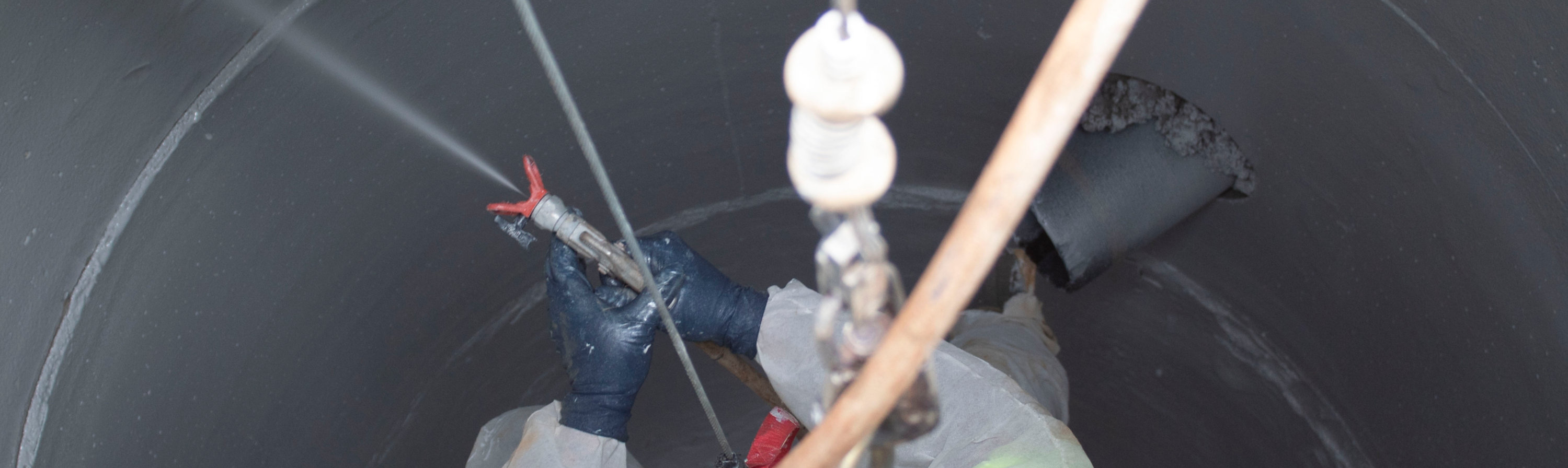 Applicator spraying a manhole