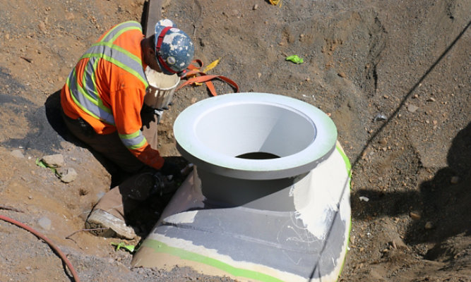 Applicator brushing Poly-Cote 115 on exterior of pipeline access manway