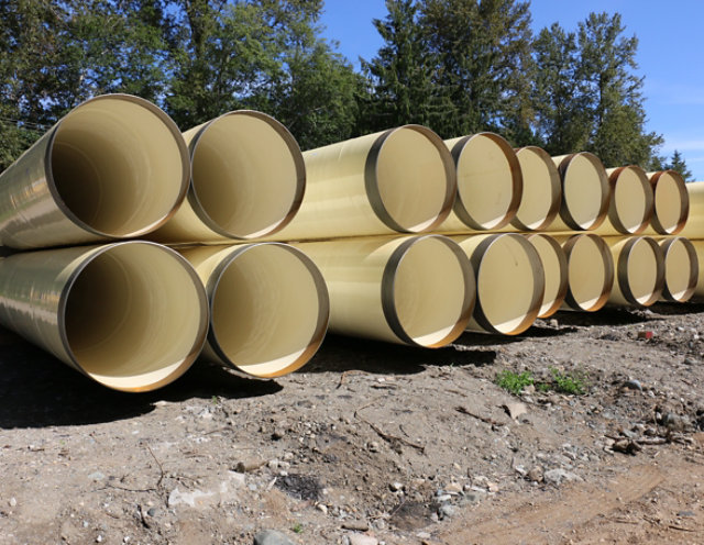 Shop-applied cream colored coating on water transmission pipes in a row and stacked