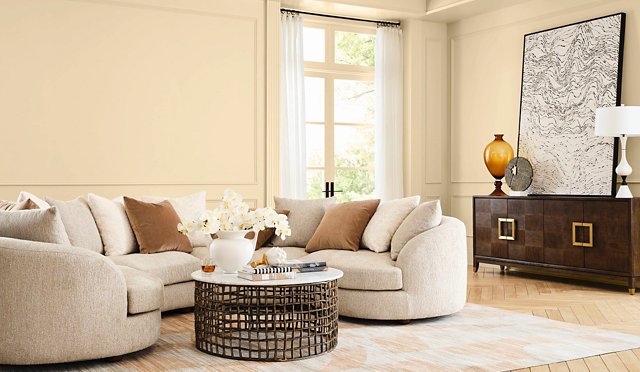 Elegant living room featuring a neutral-toned sectional sofa, wooden furniture with a smooth finished surface, and warm natural light, showcasing a refined wood interior aesthetic.