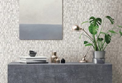 A concrete side table with a small plant in front of a tiled wall.