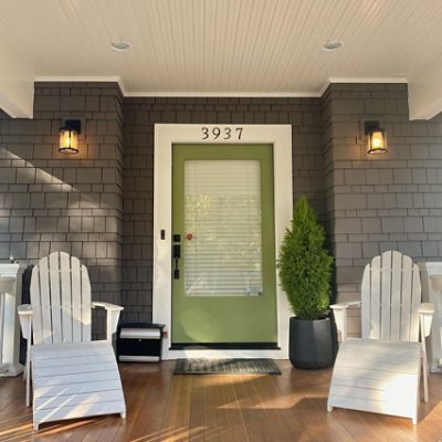 Two adirondack chairs on a front porch.