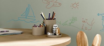 A wooden children's desk with wall drawings and crayons. 