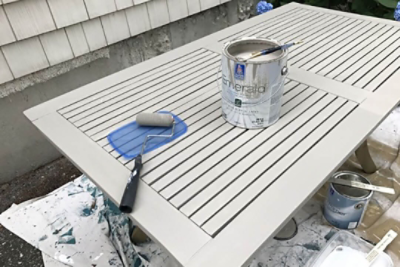 Applying exterior paint to an outdoor patio table.