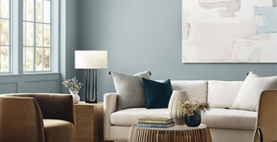 Living room painted in light blue SW paint with a cream colored couch and light brown chair with matching accents.