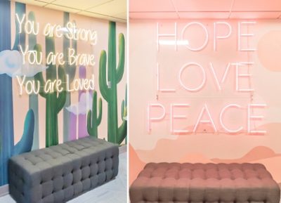 Tufted bench in front of an art-panel wall with an inspirational phrase neon sign.