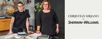 Christian Siriano and Sue Wadden, both dressed in black, standing at a table covered in paint samples in Siriano's home.