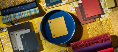 Flat lay of paint chips from The Loneliest Color™ by Sherwin-Williams x Dapper Dan Color Collection displayed with other coordinating fabrics and material swatches.