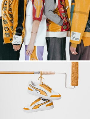 Studio photo of four models, shown from shoulder to knee, all wearing pieces of wearable art from Dapper Dan’s custom The Loneliest Color collection. Custom-designed white sneakers with Kingdom Gold details hanging by the shoelaces from a horizontal paint roller.