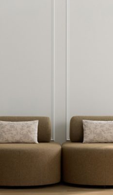 A chic sitting area with two round beige chairs, accent pillows, side tables, and small sconces against a paneled wall painted in Sherwin-Williams White Snow.
