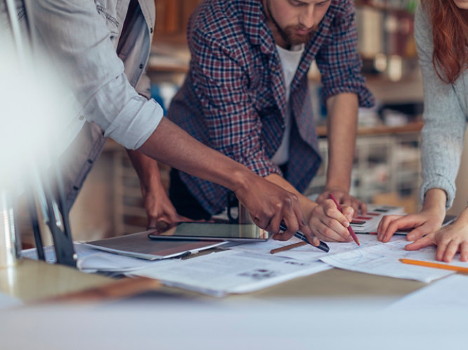 equipo de arquitectos reunido en torno al documento de planificación