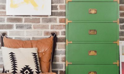 A green laminate dresser in front of a brick wall, leather chair, and wall prints